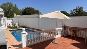 a pool with an umbrella next to a white fence at El Siprer in Anna