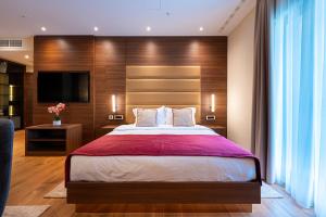 a bedroom with a large bed and a flat screen tv at Hotel De‘Andros Virpazar in Virpazar