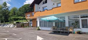 a building with a table and an umbrella in a parking lot at Motel Dreams in Novi Travnik