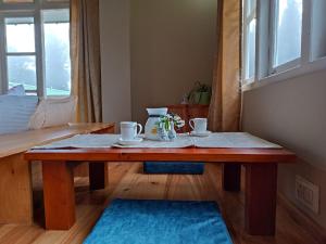 a wooden table with two cups on it in a room at The Alpine Jungle Stay in Ravangla