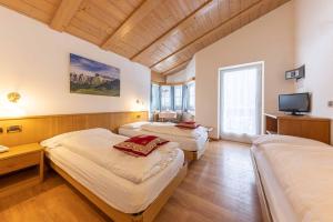 a room with two beds and a television in it at Albergo Arnica in Canazei