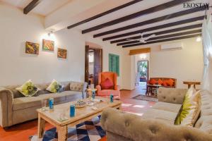 a living room with couches and a table at EKOSTAY Gold - Oasis Villa in Saligao +24 photos