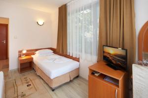 a hotel room with a bed and a flat screen tv at Nirvana Guest House in Nesebar