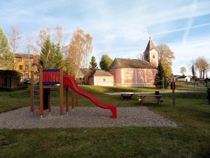 a playground with a slide in a park with a church at U Votápků in Nové Hutě