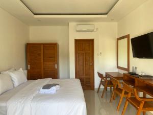 a bedroom with a bed and a desk and a television at Kusuma Life in Kerobokan