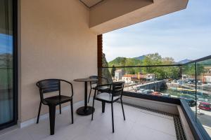 a balcony with two chairs and a table and a window at Hotel De‘Andros Virpazar in Virpazar