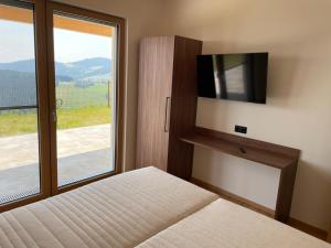 a bedroom with a bed with a tv and a window at Bergchalet mit Panoramablick Diex in Diex