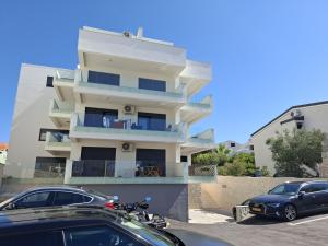 a building with two cars parked in front of it at Apartman Plesa in Povljana