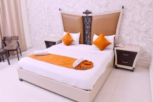 a bedroom with a large bed with orange pillows at Nirmal Hotel And Resort in Bareilly