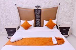 a bedroom with a large bed with orange and white pillows at Nirmal Hotel And Resort in Bareilly