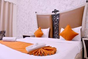 a bedroom with two beds with orange and white pillows at Nirmal Hotel And Resort in Bareilly