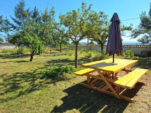 a picnic table with an umbrella and a bench at Yourte traditionnelle mongole in Marcoux