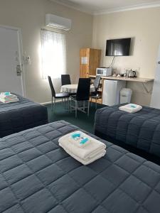 a hotel room with two beds and a kitchen at Fairway Lodge Motel in Kempsey