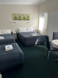 a hotel room with two beds and a table and chairs at Fairway Lodge Motel in Kempsey