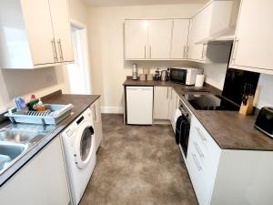 a kitchen with white cabinets and a washer and dryer at Douglas House, near Hospital, attractive and comfy 2 bedroom House with enclosed yard to rear in Carlisle +11 photos