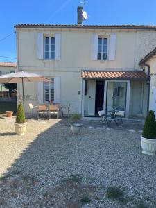 a white house with an umbrella and a patio at Gîte le clos in Saint-Sulpice-de-Faleyrens