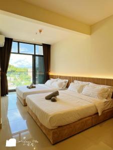 two beds in a bedroom with a large window at The Shore Maison Life 小居屋 in Kota Kinabalu