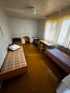 a room with two beds and a table and a table at Vasaras mājiņa pie Rāznas ezera Nr 17 in Ragi +3 photos