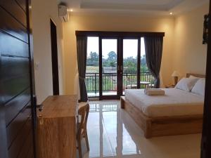 a bedroom with a bed and a balcony at KRISNA TAPAN GUEST HOUSE in Ubud
