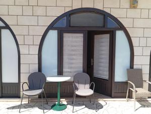 three chairs and a table in front of a building at Apartman Mara in Neum
