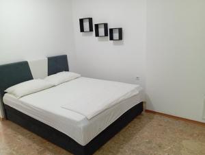 a bed in a room with a white wall at Apartman Mara in Neum