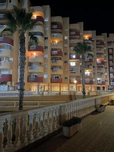 two palm trees in front of a large building at La Manga del Mar Menor, Los Miradores del Puerto in La Manga del Mar Menor