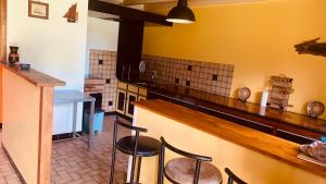 Una cocina con encimera y taburetes en una habitación. en Maison Rumoal, en Saint Hernin