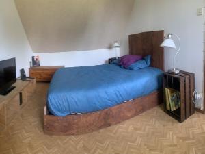 Un dormitorio con una cama grande con una manta azul. en Maison Rumoal, en Saint Hernin