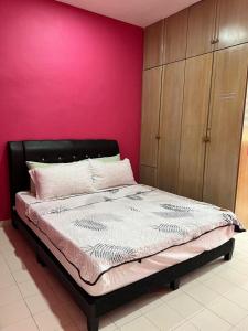 a bed in a bedroom with a pink wall at Batu Feringgi Homestay in Batu Ferringhi +34 photos