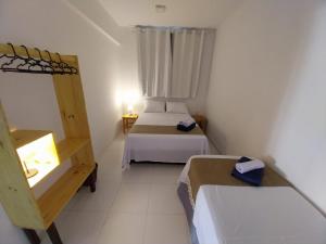 a small room with two beds and a window at Jardim das Dunas in Canoa Quebrada