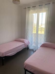 two beds in a room with a window at Appartamento fronte spiaggia climatizzato in Ardore Marina