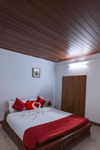 AnachalにあるBuddha Mayuri Homestayのベッドルーム1室(大型ベッド1台、赤い枕付)