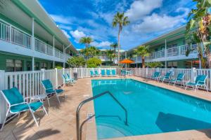 a swimming pool at a resort with blue chairs and palm trees at Tropic Terrace Suite #24 - Beachfront Resort in St Pete Beach