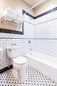 a white bathroom with a toilet and a bath tub at Hip Urban Loft - Small Town Charm - 124 LOFTS #4 in West Dundee