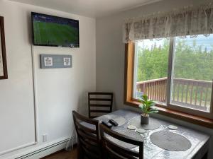une salle à manger avec une table avec des chaises et une télévision dans l'établissement Peaceful Acres Cabin 3 - Soldotna, AK, à Kasilof