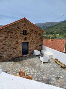 Un patio de piedra con sillas blancas y un edificio. en Lugar da Borralheira, en Verdelhos 44 fotos más