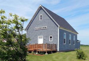 a large church with a gambrel roof and a deck at Old Schooling Summer Cottage in OʼLeary +8 photos