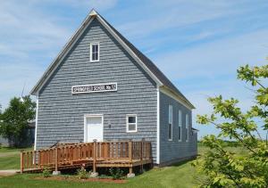eine kleine blaue Kirche mit einem Holzdeck auf einem Feld in der Unterkunft Old Schooling Summer Cottage in OʼLeary