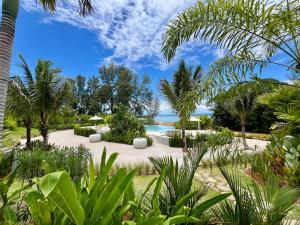 ein Garten mit Pool und Palmen in der Unterkunft Cape Pakarang Wow Wild Wellness Escapes in Khao Lak