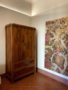 a wooden cabinet in a room with a painting at Appartamento Bilocale in Riolo Terme