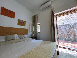 a bedroom with a bed and a large window at Villa Velta Sea Sunset in Porto Santo Stefano