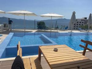 a swimming pool with a table and an umbrella at Dioneida Apartments in Sarandë