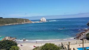 a beach with a large rock in the ocean at Algarrobo Apartment in Algarrobo