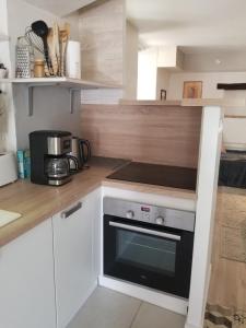 a kitchen with white cabinets and a black oven at Maison au pied du château, terrasse in Grignan +16 photos