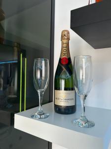 a bottle of wine and two wine glasses on a shelf at Love spa apartman in Banja Koviljača