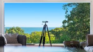 a camera on a tripod in front of a window at 'Putty Beach Retreat' by HolidayCo in Killcare