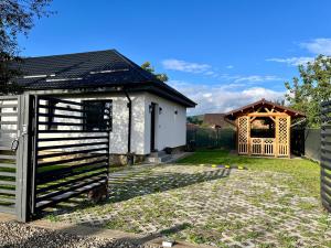 a white house with a gate and a gazebo at Casa Ilinca in Dărmăneşti