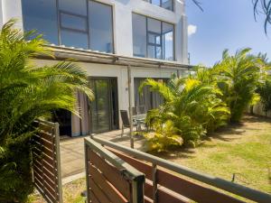 a house with a wooden fence and palm trees at Appartement avec jardin Cap Malheureux in Cap Malheureux