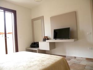 a bedroom with a bed and a tv on a wall at HomeStyle Agorà in Villasimius