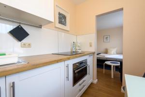 a kitchen with white cabinets and a bed in a room at Bremer Apartmenthotel Superior in Bremen